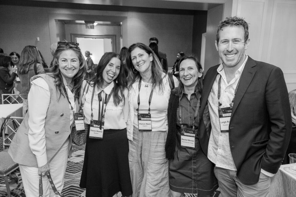 Group of people wearing conference lanyards pose for a photo.