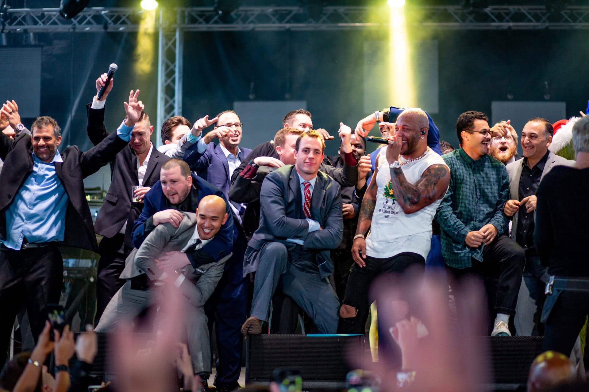 Group of men in suits on stage with a rapper