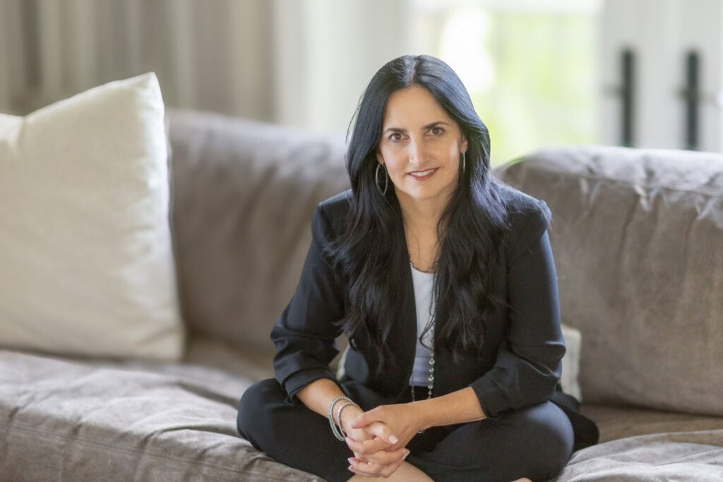 A woman sits cross-legged on a couch