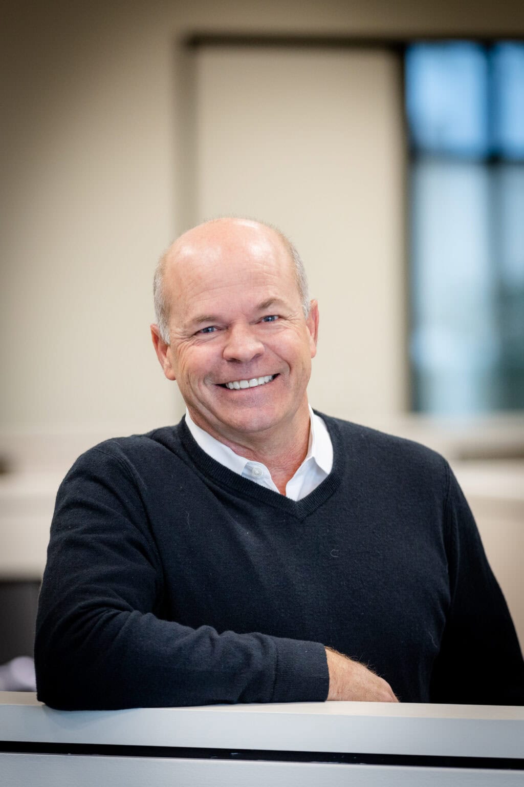 A man smiling with his arm on top of a cubicle wall