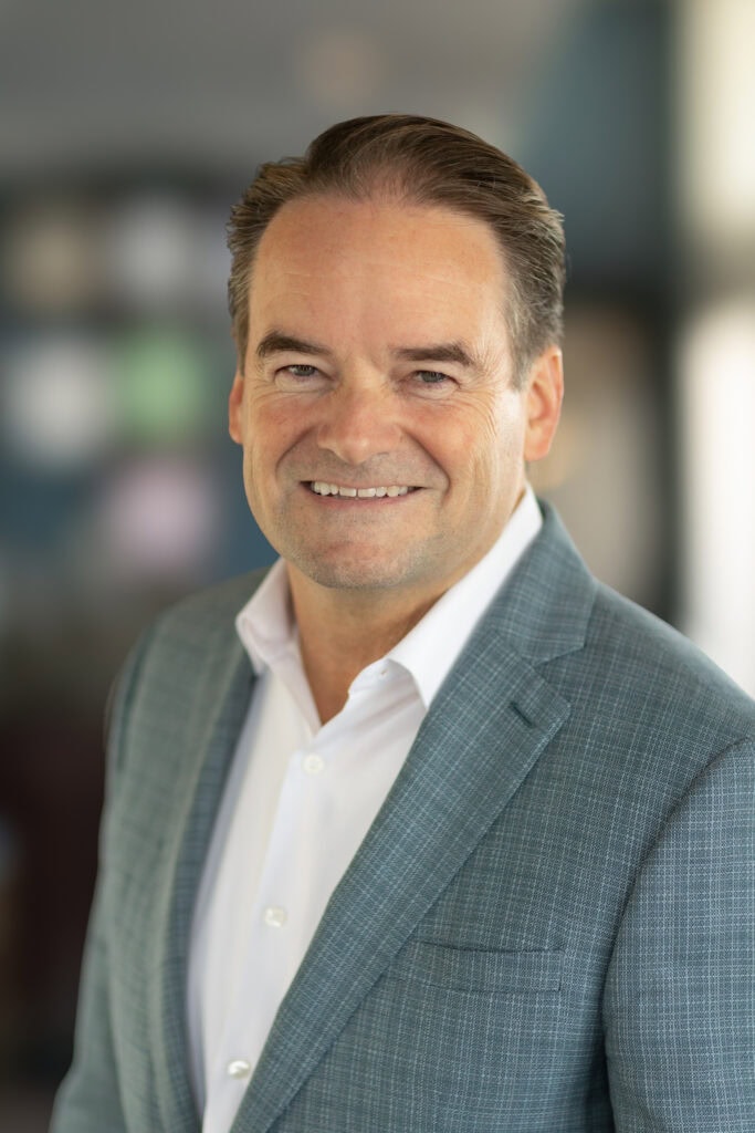 Headshot of a main in a grey blazer