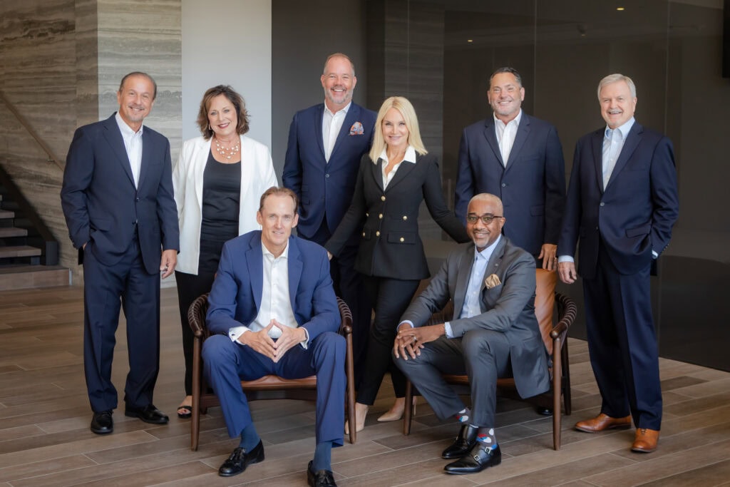 A formally posed group of 8 business team members in formal wear