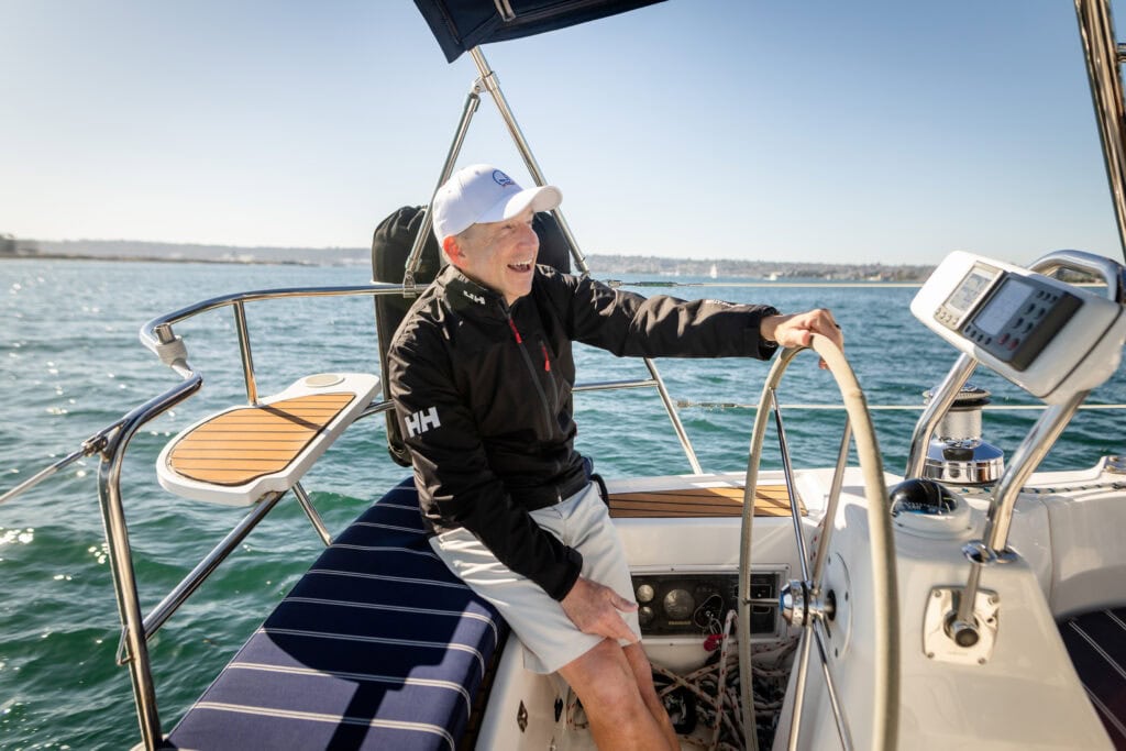 A man holds the wheel of a sailboat