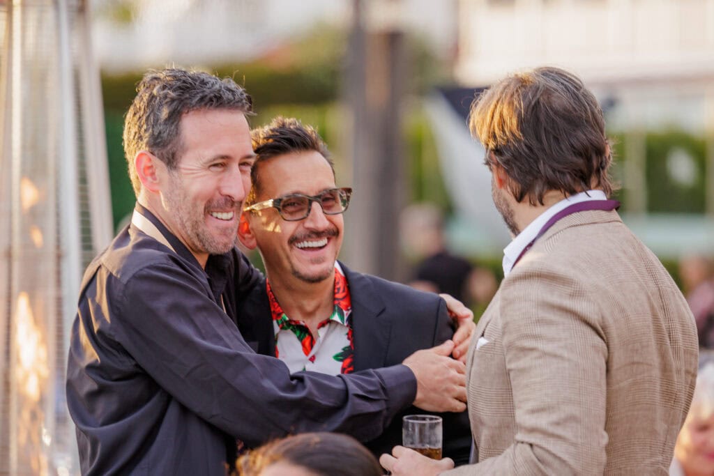 People embracing and smiling outdoors during a business event