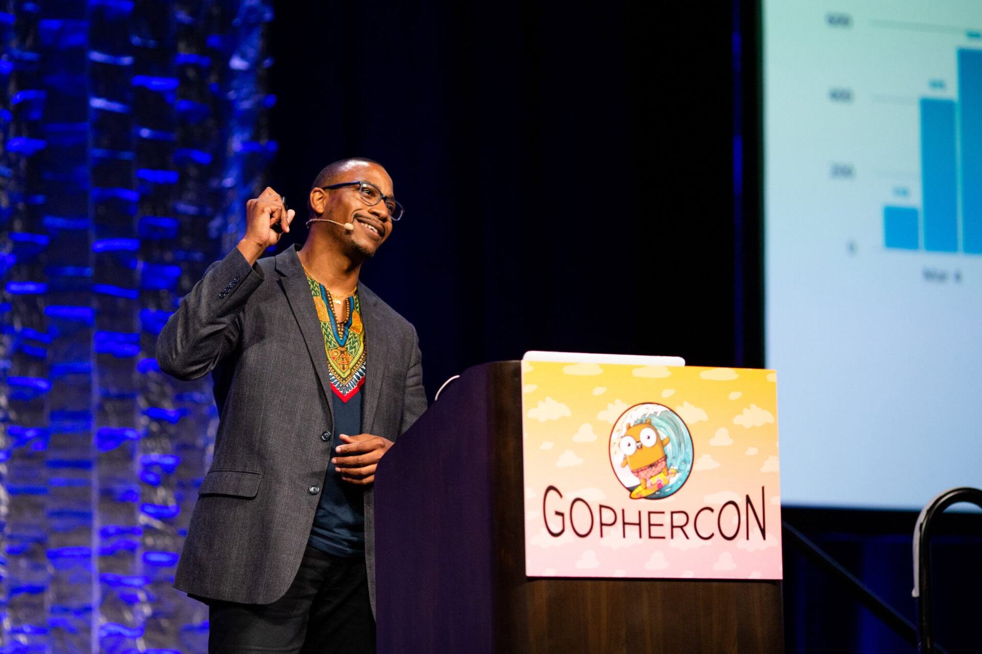 Gophercon presenter A man at a podium smiling while giving a presentation during Gophercon