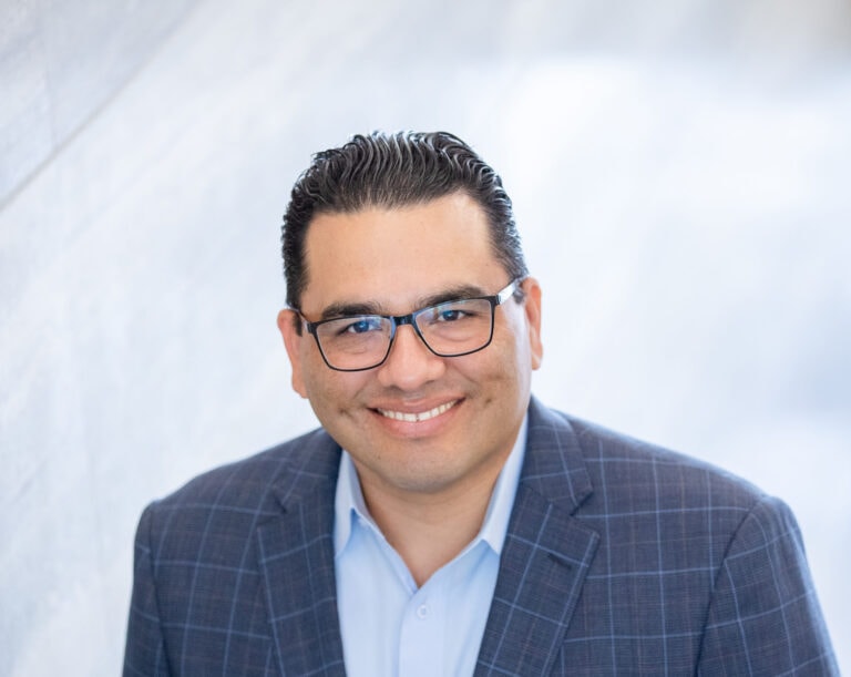 Headshot of a man with dark hair and glasses.
