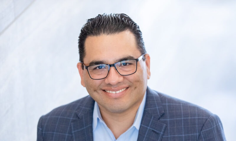Headshot of a man with dark hair and glasses.