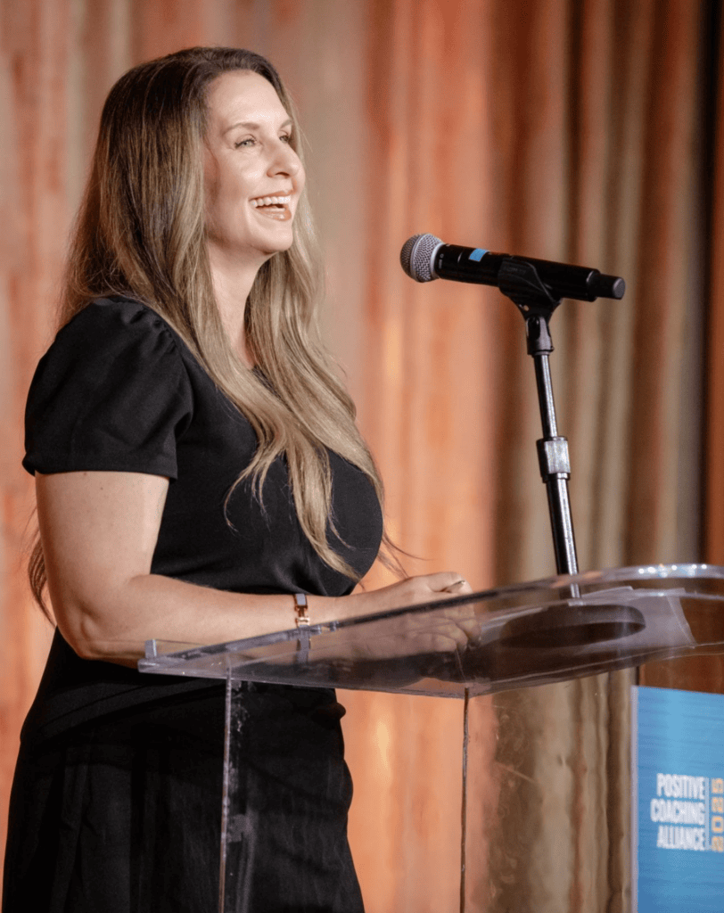 A women in a black dress speaks at a podium