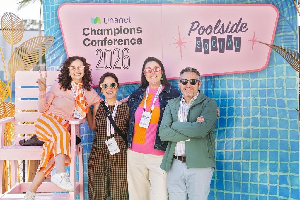 Group of four people posing at a conference backdrop with Poolside Social branding.