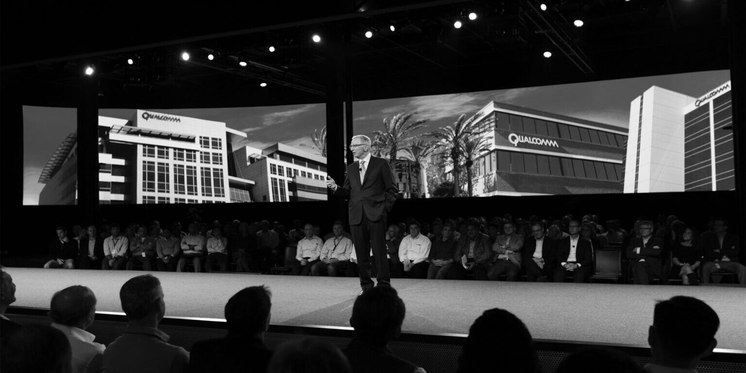 Man in a suit speaking on stage at a convention