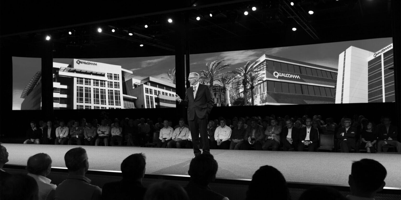 Man in a suit speaking on stage at a convention