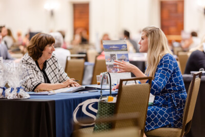 Two people conversing at a table during a business event
