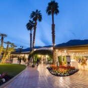 Hotel courtyard at dusk with lights and palm trees