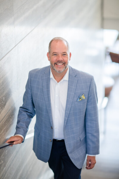 Portrait of a man in a blue blazer on the staircase of a modern office building