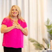 A woman presenting at a business event holds her hands over her heart