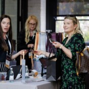 A woman working a sponsor table at a business conference talks to conference goers