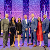 A group of executives pose on stage during a business conference