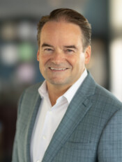 Headshot of a main in a grey blazer