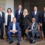 A formally posed group of 8 business team members in formal wear