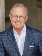 Headshot of a man in a blazer with glasses