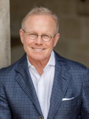 Headshot of a man in a blazer with glasses
