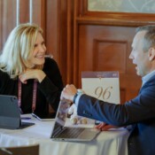 A woman and a man in conversation with laptops open on a small table