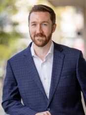 Outdoor headshot of a man posing in a blazer