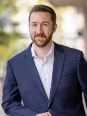 Outdoor headshot of a man posing in a blazer