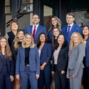 A group of people in business attire pose in front of an office building