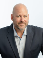Headshot of a bald man in a dark blazer