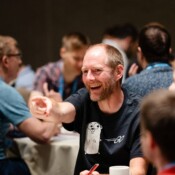 A man in the audience smiles and points during a conference