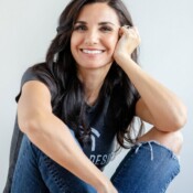 A woman seated with her legs crossed and smiling